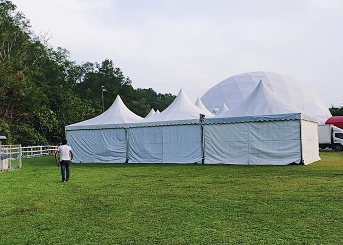 A large, white tent rental unit in display at a field.